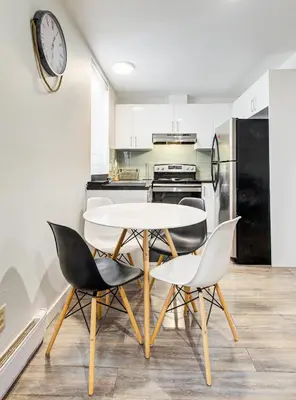 a kitchen with a table and chairs and a clock on the wall at Griffintown Central 2BR in Montréal