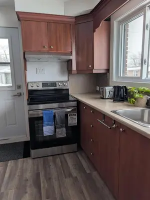 a kitchen with wooden cabinets and a stove and a sink at Chambre confortable 2 pas Hôpital Université Services in Trois-Rivières