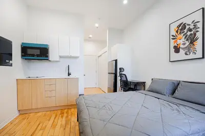 a bedroom with a large bed and a kitchen at Studio 2 voyageurs-séjour hebdomadaire-Parking gratuit in Montréal