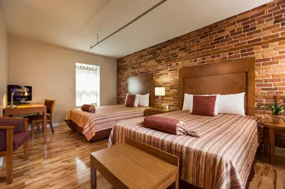 a hotel room with two beds and a brick wall at Hotel Quartier des Spectacles in Montréal