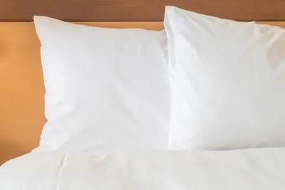 a bed with white sheets and pillows on it at Holiday Inn Express Hotel & Suites Saint - Hyacinthe by IHG in Saint-Hyacinthe