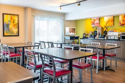 a restaurant with tables and chairs and a kitchen at Comfort Inn South in Brossard