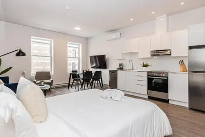 a white kitchen with a large bed in a room at Modern and New Studio in the Heart of the City by Den Stays in Montréal