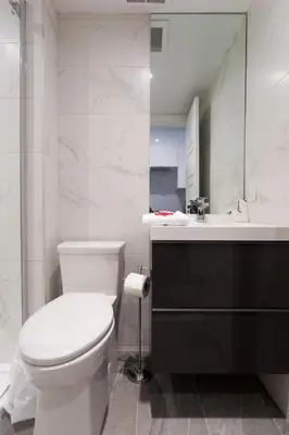 a white bathroom with a toilet and a sink at Blue Tropics Studio in Little Italy with kitchen by Den Stays in Montréal