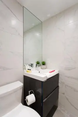 a white bathroom with a sink and a mirror at The Santamaria Golden Palms Studio by Den Stays in Montréal