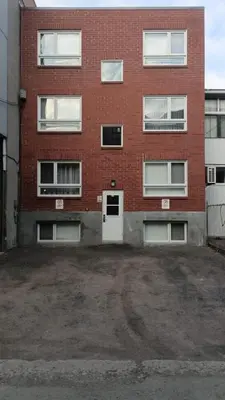 an empty parking lot in front of a brick building at The Santamaria Golden Palms Studio by Den Stays in Montréal