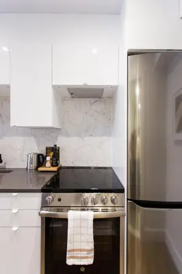 a kitchen with a stove and a stainless steel refrigerator at Romantic Studio in the Heart of Little Italy by Den Stays in Montréal