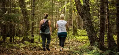 two women walking on a trail in the woods at Bel appartement A la croisée des sommets in Notre-Dame-Des-Bois