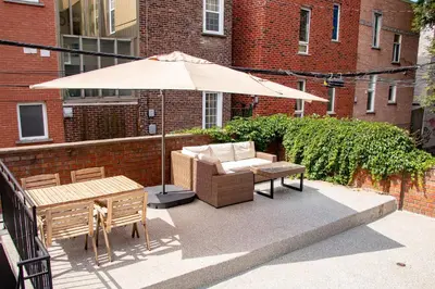 a patio with an umbrella and a couch and a table at GATSBY - SelfCheckIn - Rooftop - Terraces - St-Denis in Montréal
