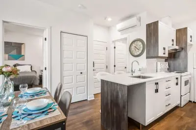 a kitchen with white cabinets and a table with chairs at Le Mile End by M11 - Upscale 1 BDR with Sofa Bed in Montréal