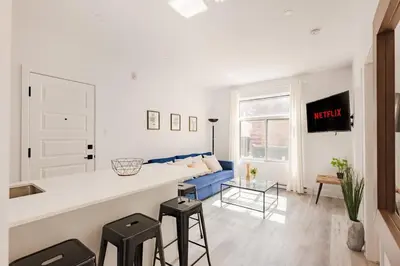 a kitchen and living room with a counter and stools at Le Mile End by M11 - Spacious 2BDR Unit with Sofa Bed in Montréal