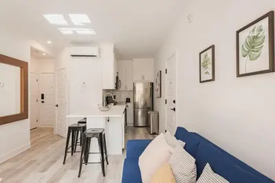 a living room with a blue couch and a kitchen at Le Mile End by M11 - Spacious 2BDR Unit with Sofa Bed in Montréal
