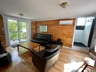 a living room with a couch and a table at La cachette de la rivière au saumon et spa in Scotstown